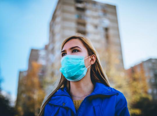woman wearing surgical mask while walking in public area
