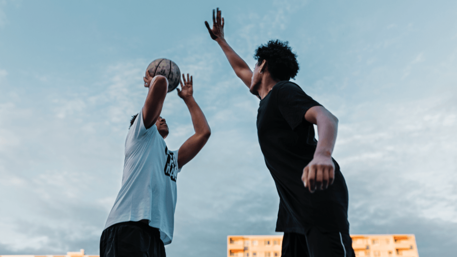 Two people playing basketball outside