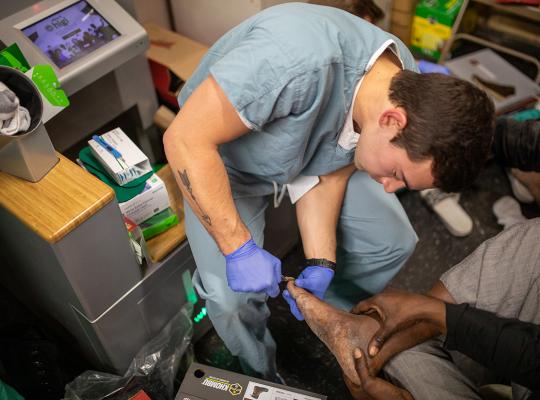 medical student provides foot care to homeless person at Franciscan House of Joseph and Mary