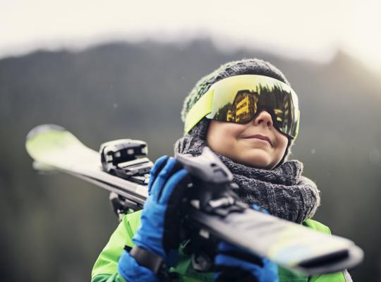 Portrait of a little skier carrying his skis stock photo